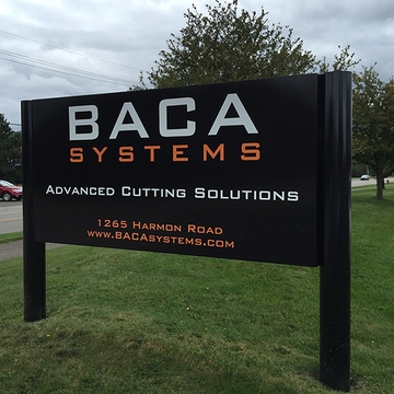 BACA Systems black post and panel sign with orange lettering by the road